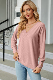Blush pink V-neck blouse with diamond texture and button cuff details