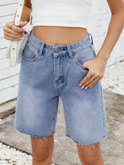 Longline denim shorts in medium wash with raw hem detail.
