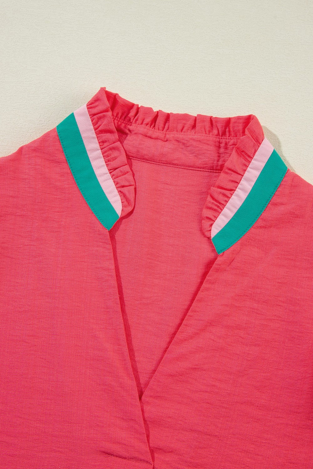 Colorblock puff sleeve blouse in strawberry pink with ruffled collar and green stripe detail.
