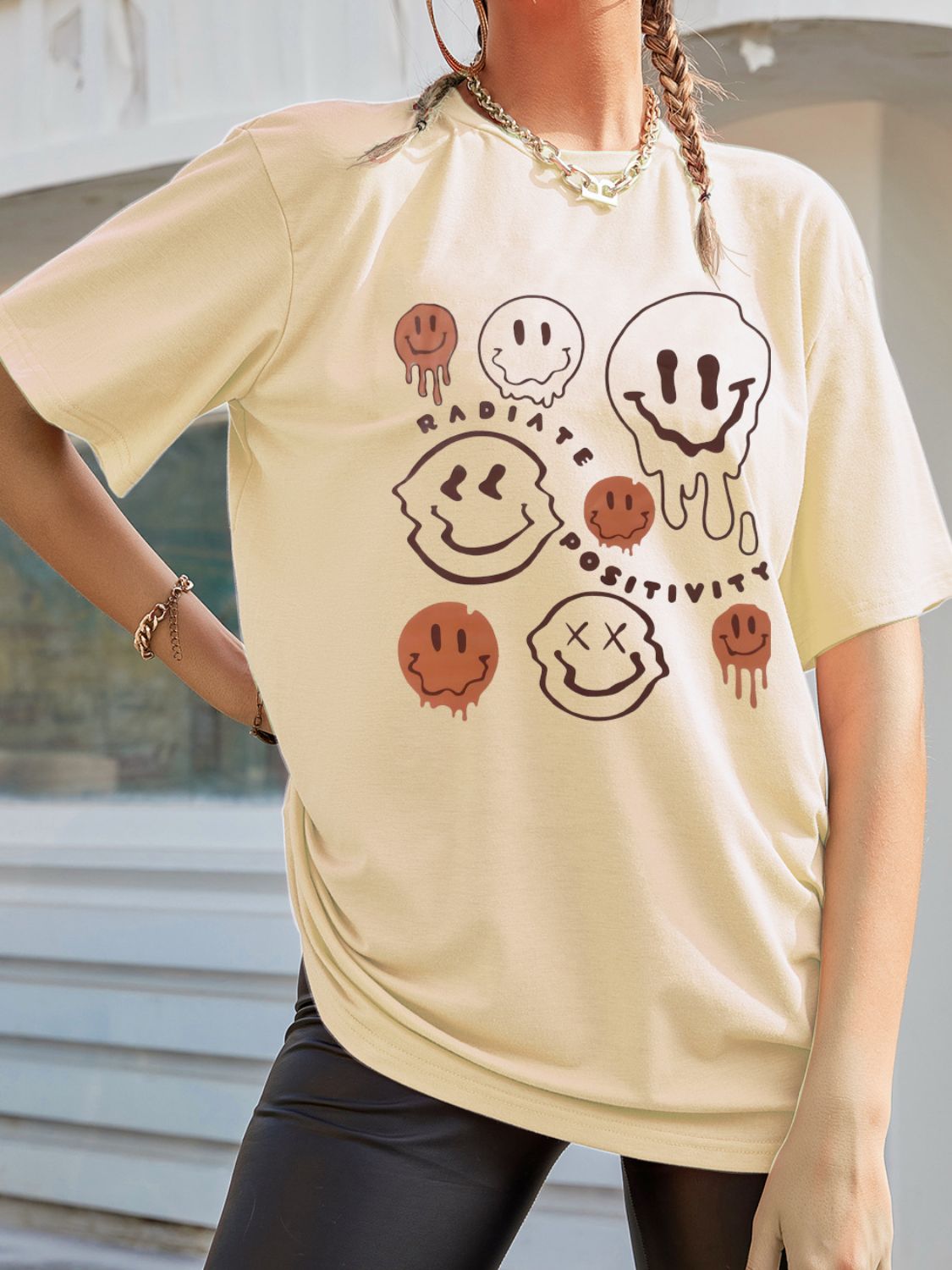 Tan oversized graphic tee with melting smiley faces and text.