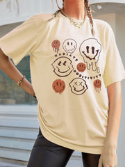 Tan oversized graphic tee with melting smiley faces and text.