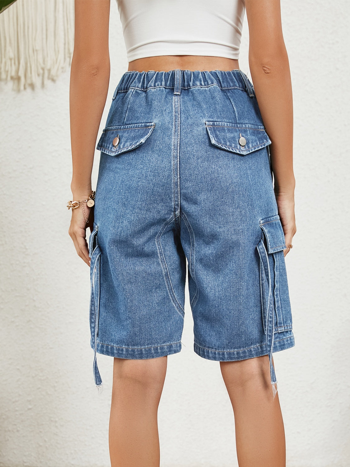Denim Bermuda shorts in medium wash with cargo pockets and buttoned back pockets.