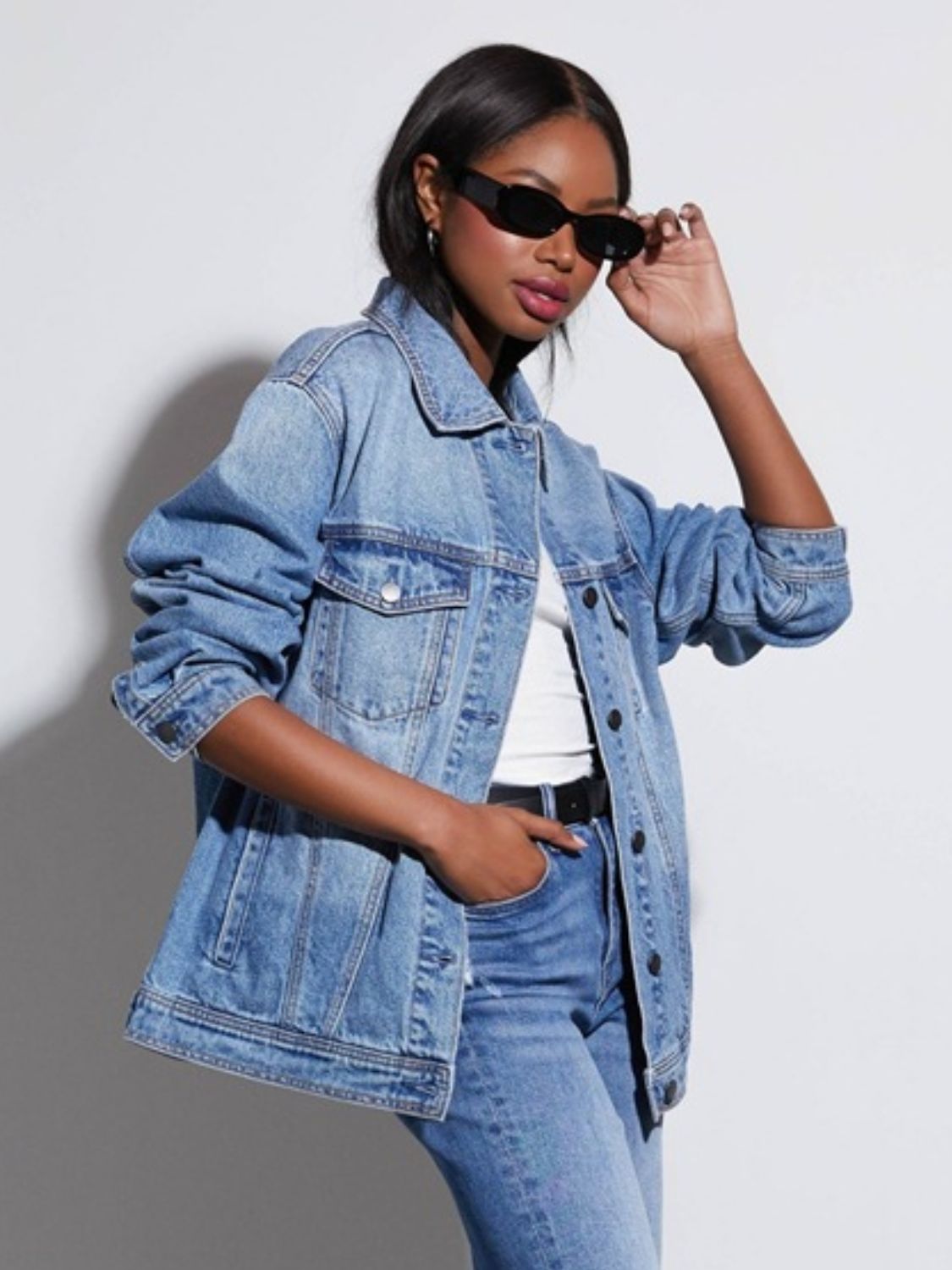 Medium wash denim trucker jacket with collar and button front, featuring chest pockets.