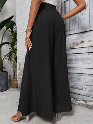 Black ruffled waistline palazzo trousers with a wide leg and textured fabric.
