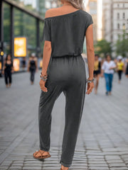 Dark gray asymmetric drape jumpsuit with drawstring waist and short sleeves.