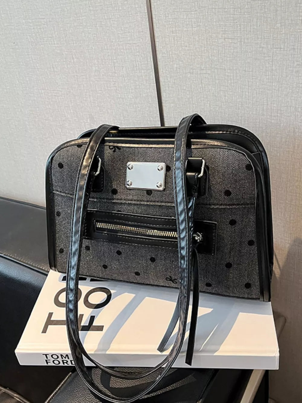 Sophisticated black polka dot shoulder bag with silver hardware and a front zipper pocket.