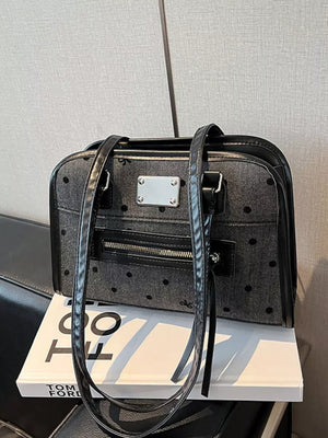 Sophisticated black polka dot shoulder bag with silver hardware and a front zipper pocket.