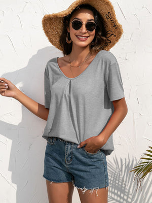 Grey t-shirt with short sleeves and a pleated neckline, styled with denim shorts.