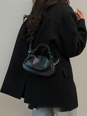 Black ruched crossbody bag with knot handle and adjustable strap.