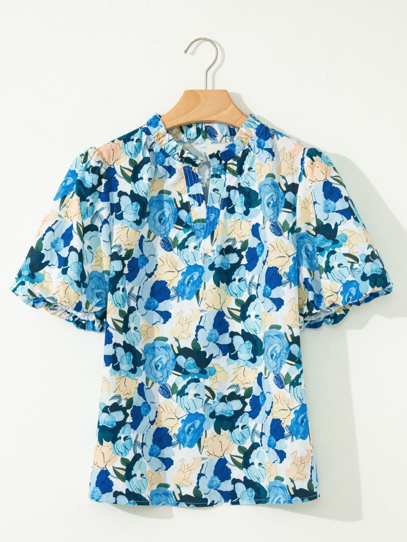 Cotton blouse with vibrant blue floral print, puff sleeves, and tie-neck detail.