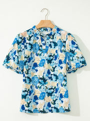 Cotton blouse with vibrant blue floral print, puff sleeves, and tie-neck detail.