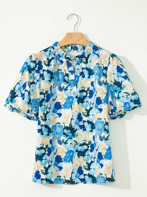 Cotton blouse with vibrant blue floral print, puff sleeves, and tie-neck detail.