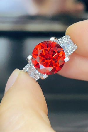 Crimson solitaire ring with pave band and accent stones.