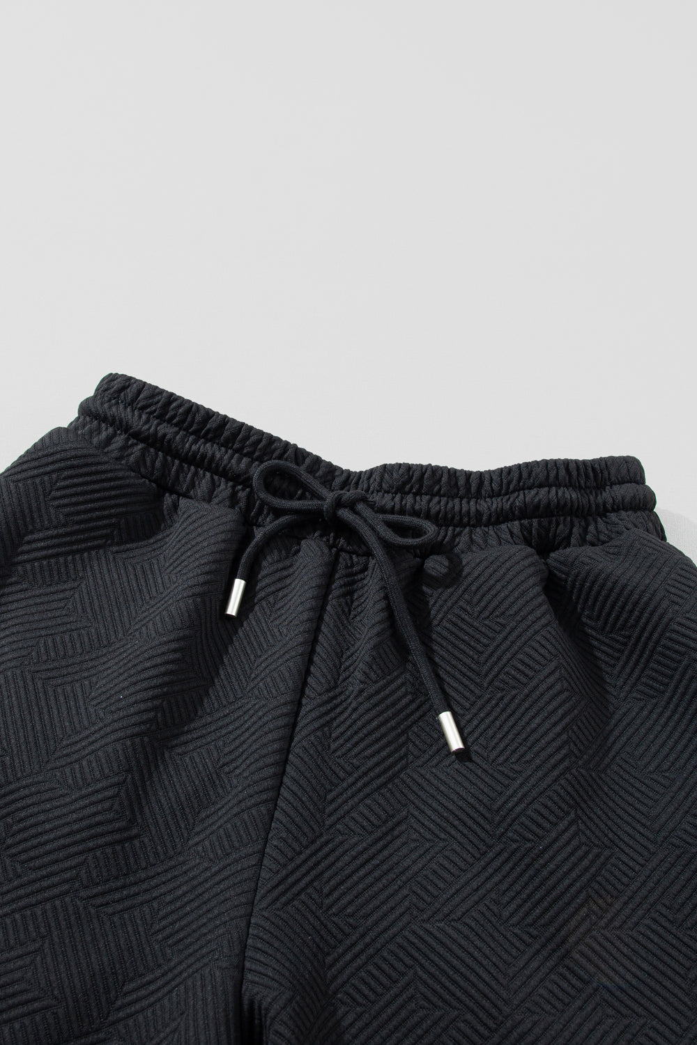 Black textured lounge pants with drawstring waist and silver-tipped ends.