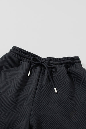 Black textured lounge pants with drawstring waist and silver-tipped ends.