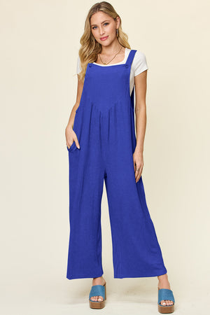Ribbed wide-leg pinafore jumpsuit in royal blue with V-neck bodice and side pockets.