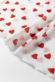 Sheer white t-shirt with red heart print, close-up detail of mesh fabric.
