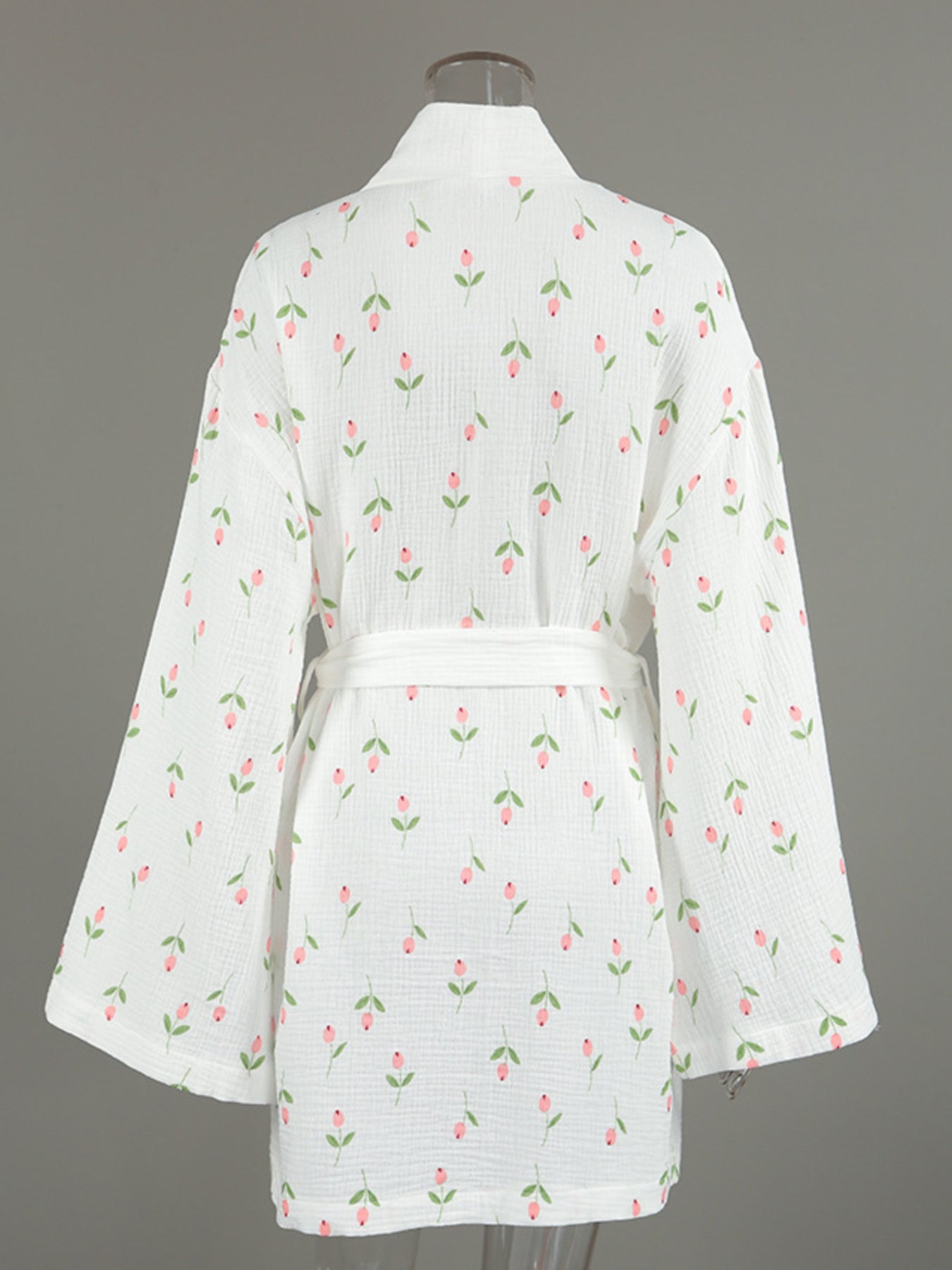White cotton robe with pink floral print and green leaves, belted waist, kimono sleeves.