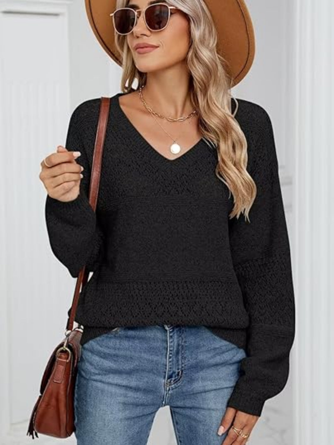 Black eyelet stitch V-neck pullover sweater with long sleeves and textured details.