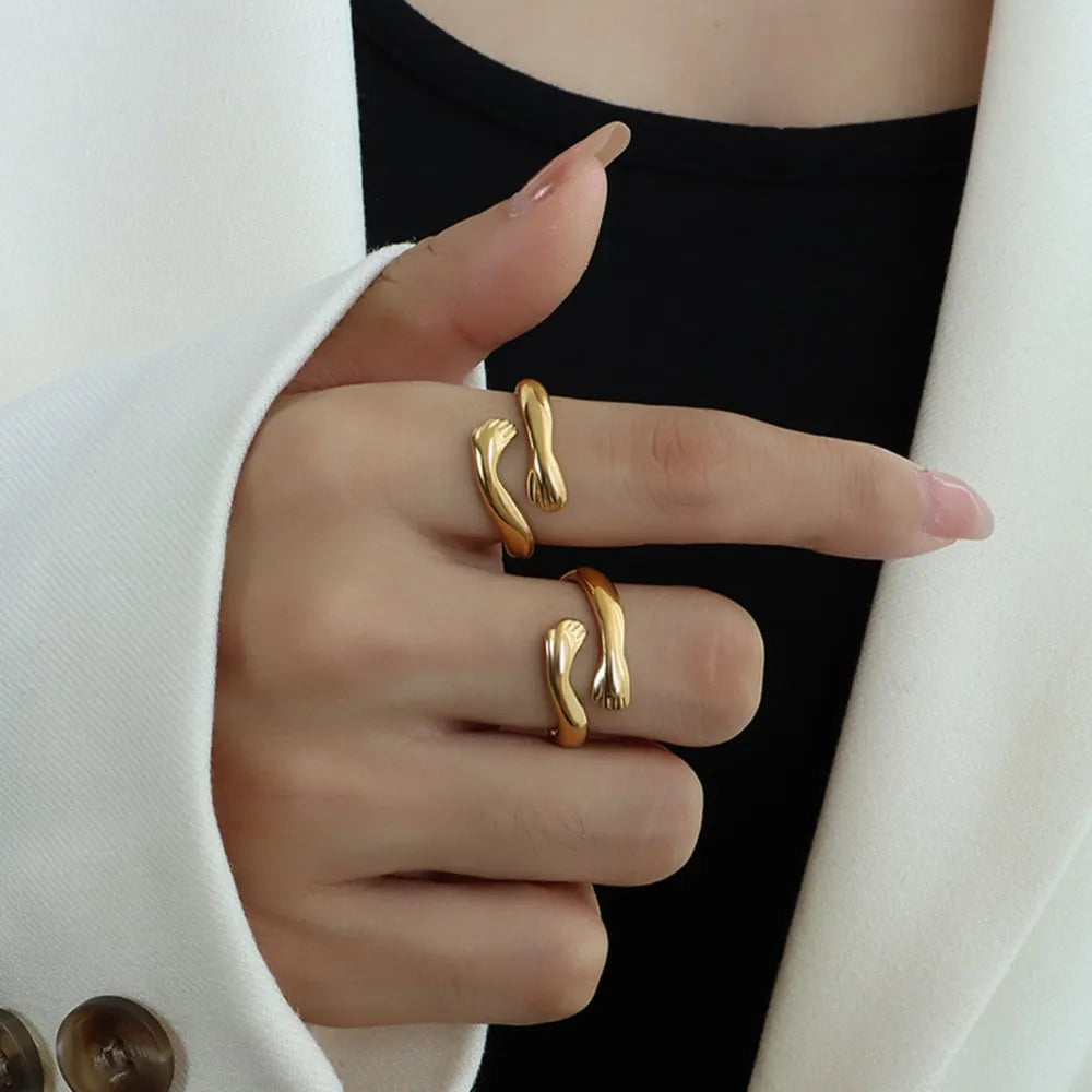 Gold embracing hands open ring on finger, chic minimalist jewelry