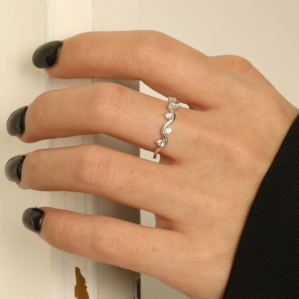 Silver band ring with wavy design and small clear stones