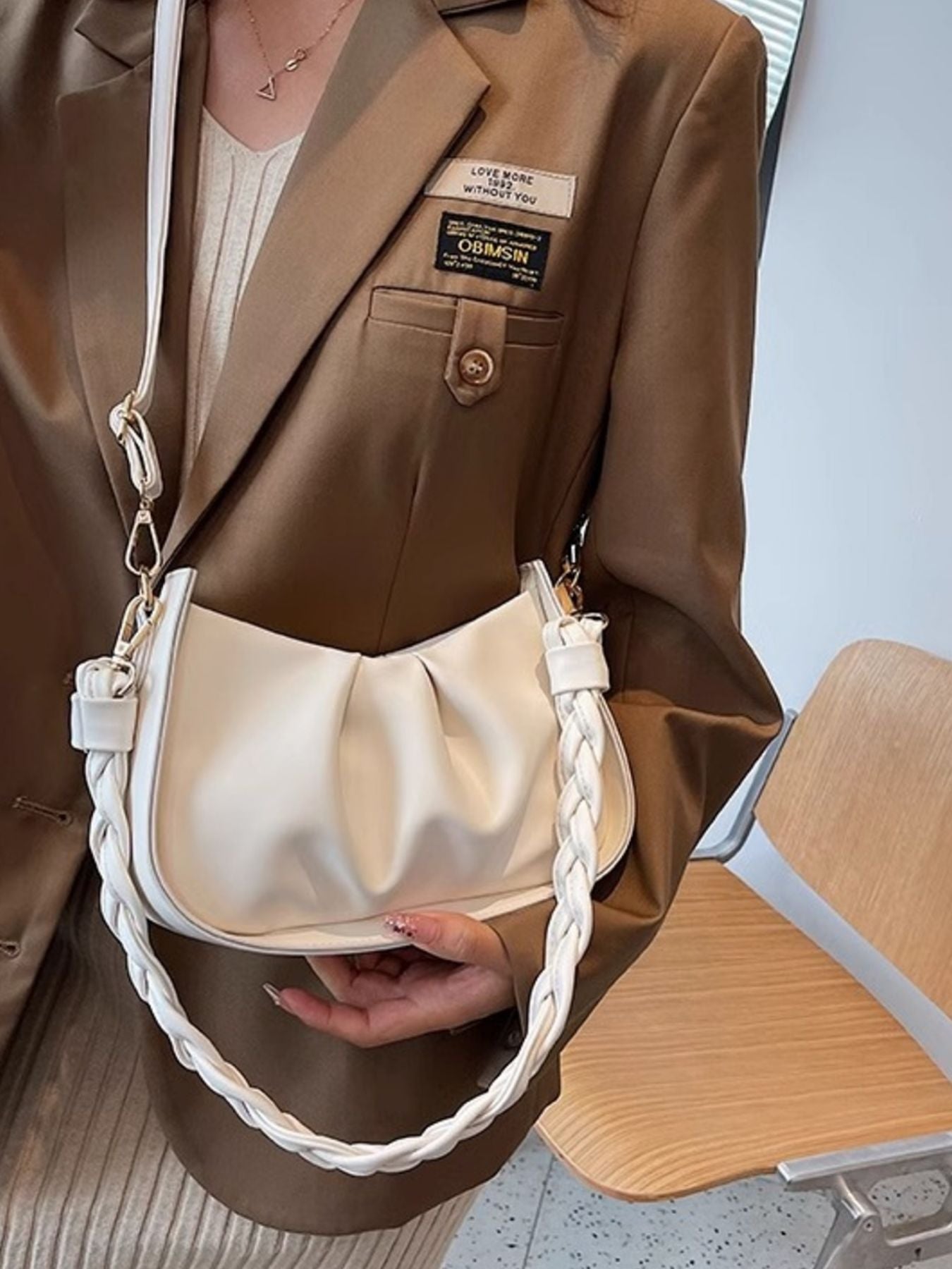 White ruched crossbody bag with braided strap detail.