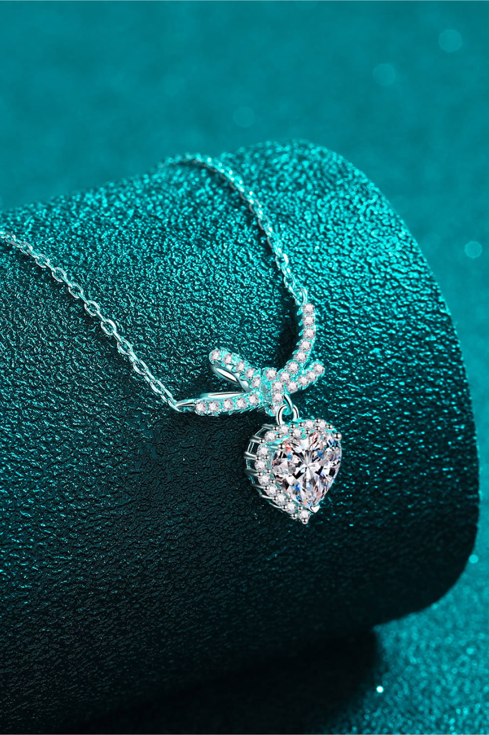 Silver necklace with cubic zirconia bow accent and heart pendant.