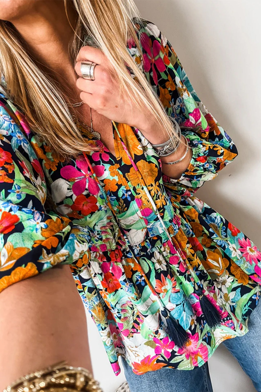 Vibrant floral print blouse with tassel trim and V-neckline.