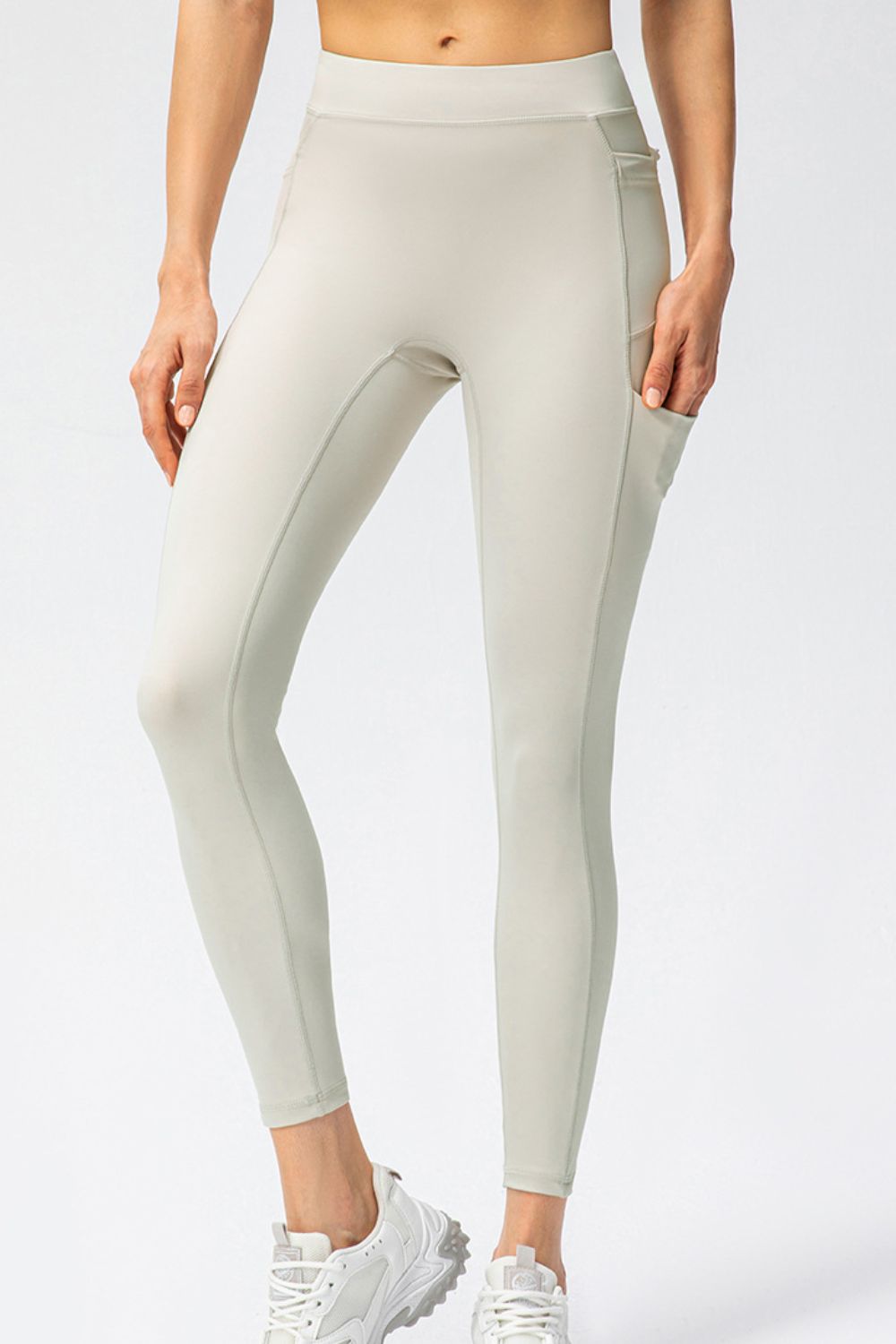 Cream athletic leggings with utility pockets and contrast stitching.