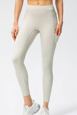 Cream athletic leggings with utility pockets and contrast stitching.