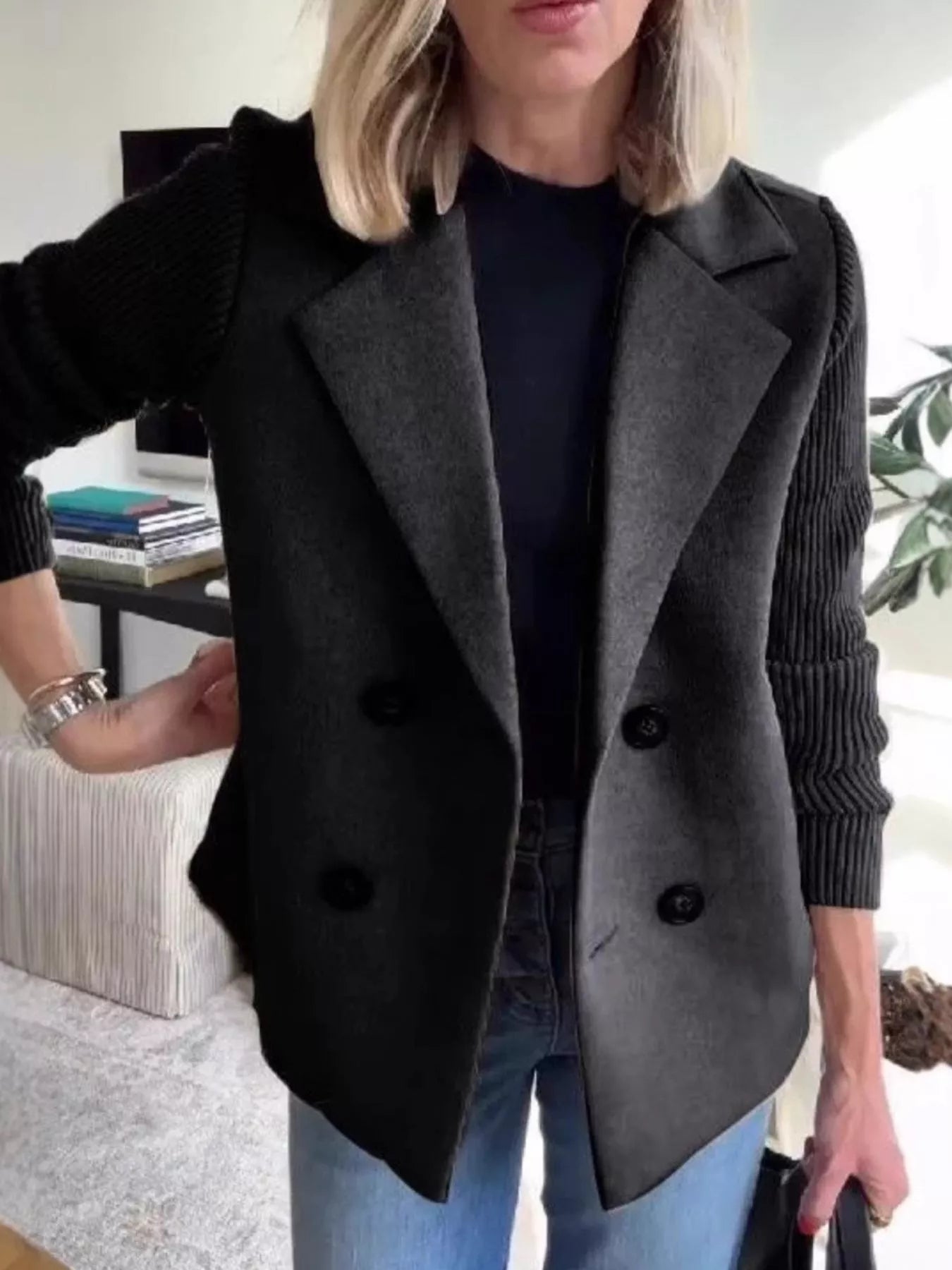 Double-breasted dark gray coat with black knit sleeves and lapel collar.