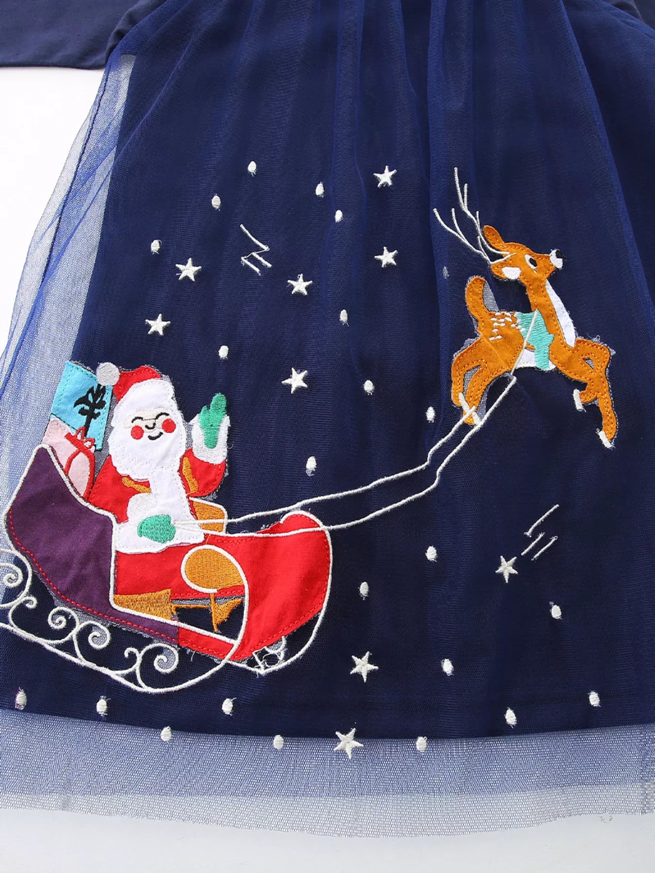 Dark navy baby dress with embroidered Santa, sleigh, and reindeer on starry tulle overlay.