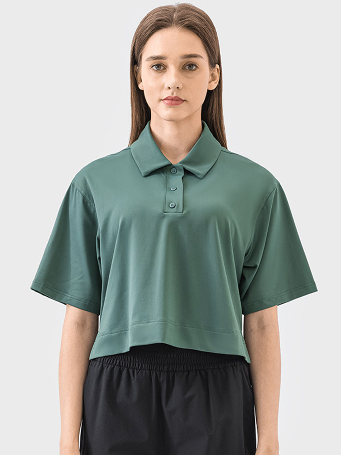 Cropped polo shirt in green with short sleeves and a button placket.