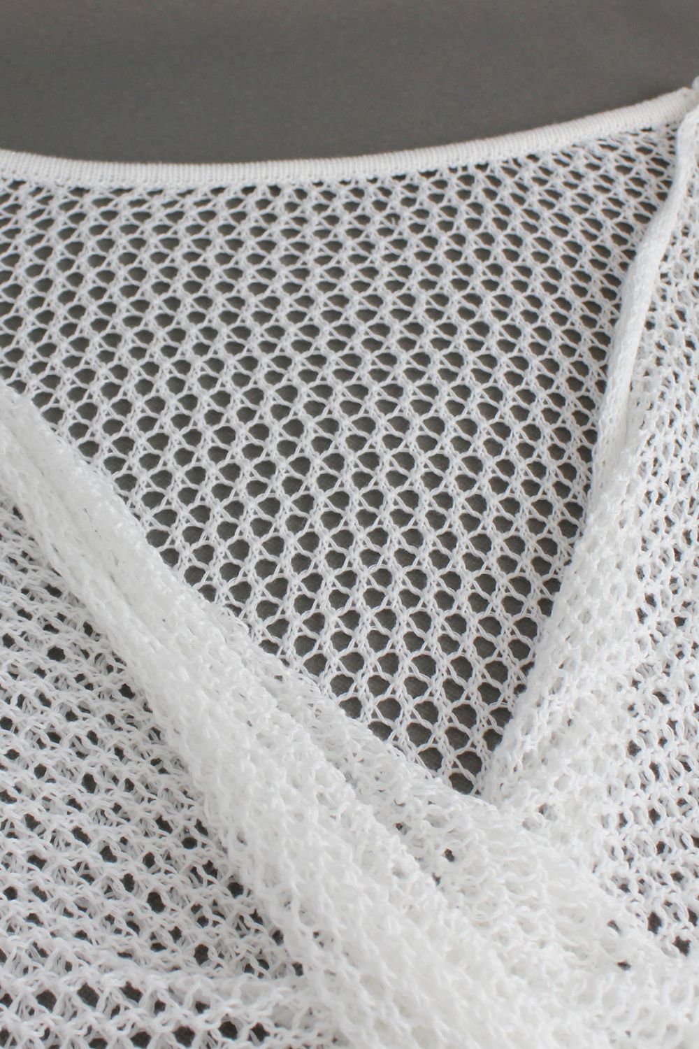 White crochet blouse with open knit detail and pearl chain strap.