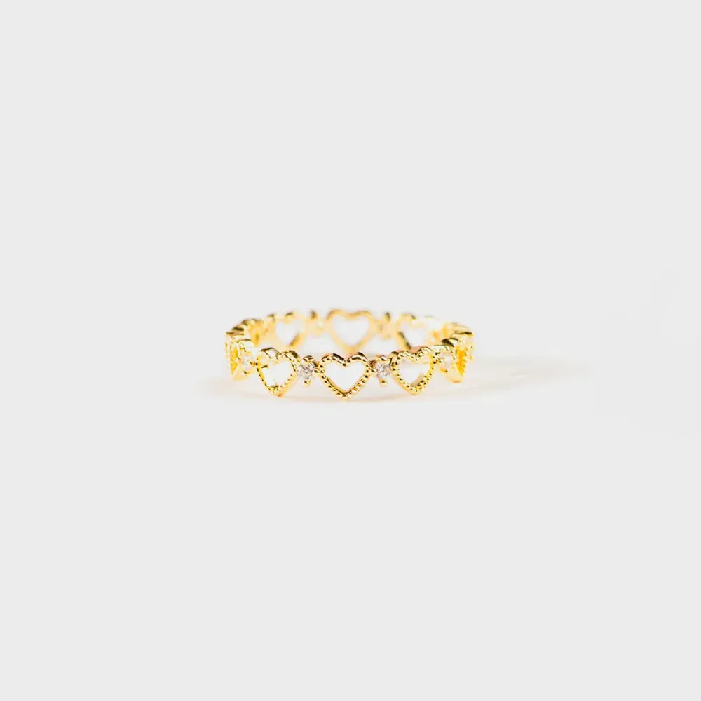 Gold ring with a repeating heart pattern and small clear stones.
