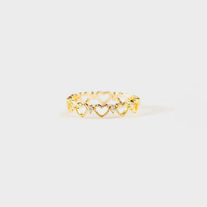 Gold ring with a repeating heart pattern and small clear stones.