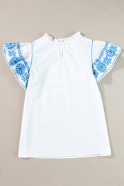 White blouse with embroidered blue floral sleeves and ruffle neckline