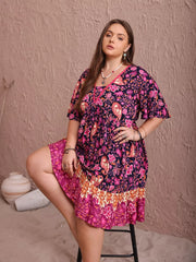 Plus-size floral flutter dress with ruched waist and tiered hem in navy, pink, and orange.