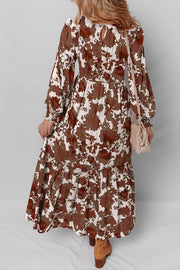 Charming floral maxi dress with billowy sleeves, smocked bodice, and tiered skirt in brown and beige cotton.