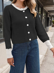 Black knit raglan sleeve cardigan with white trim and buttons, cuffed sleeves.