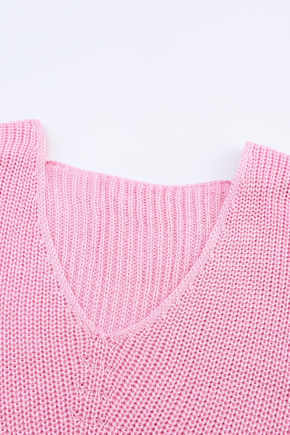 Relaxed knit v-neck pullover in blush pink acrylic with ribbed texture.