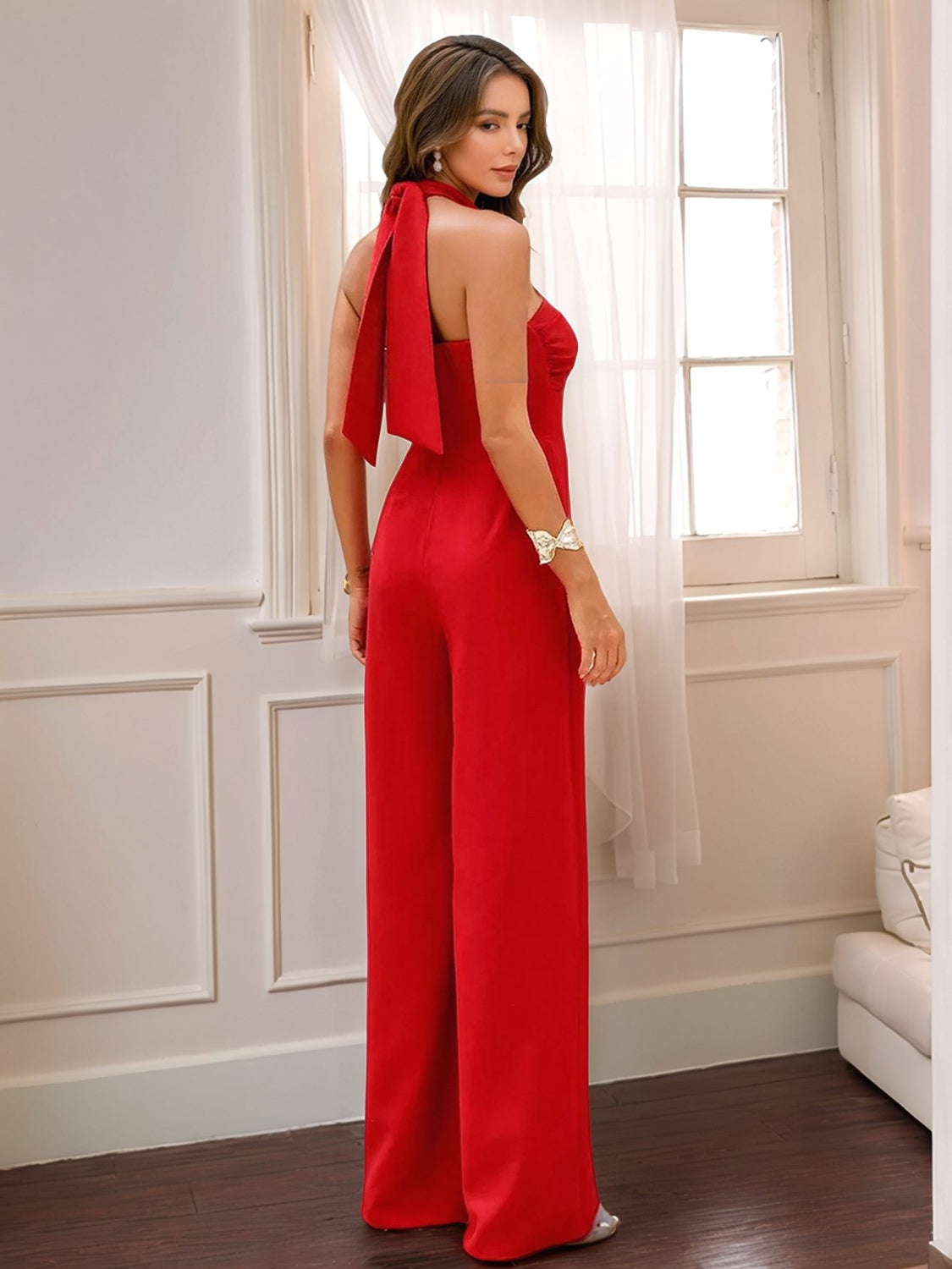 Red halter jumpsuit with wide legs and a tie detail at the neck.