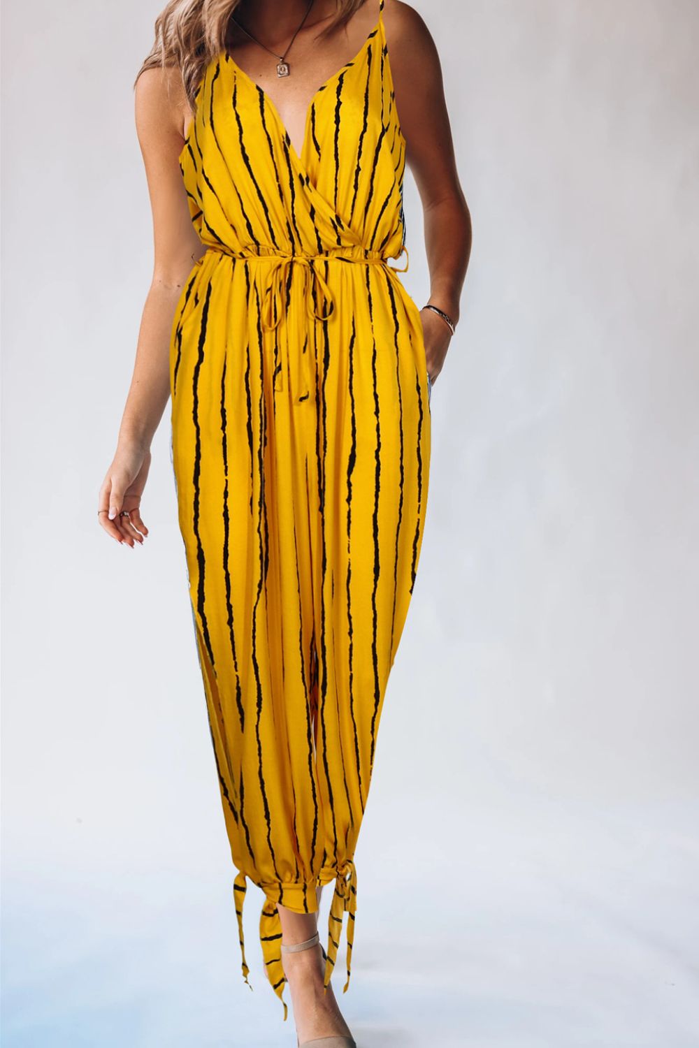 Gold wrap jumpsuit with black sunburst stripes, V-neck, tie waist, and ankle ties.