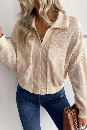 Cream teddy fleece bomber jacket with zip front and collared neck, styled with jeans.