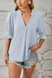 Light blue puffed sleeve blouse with flared cuffs and V-neck.