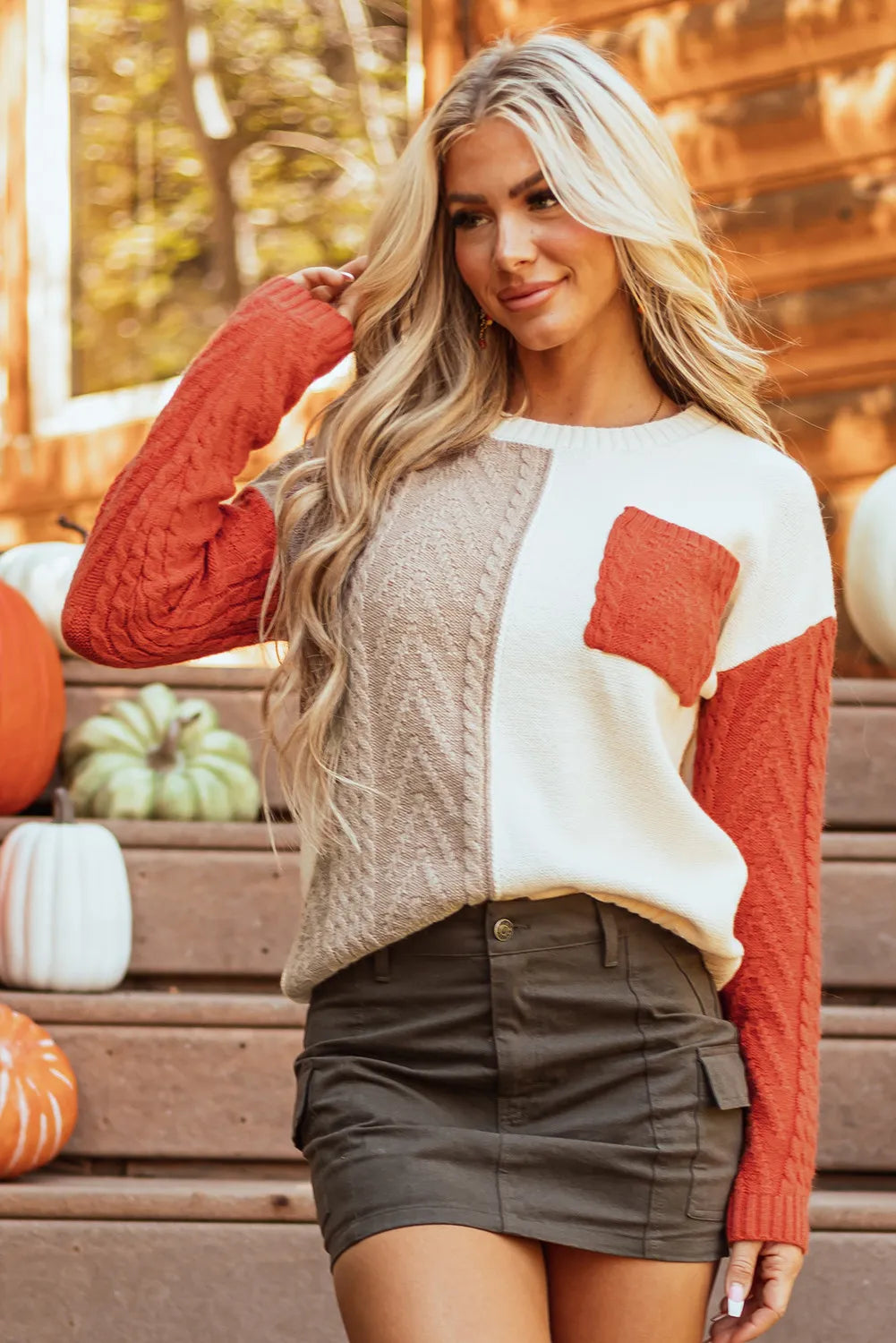 Textured panel sweater in cream, tan, and orange with cable knit sleeves and chest pocket.