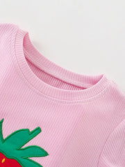 Pink ribbed cotton baby tee with strawberry graphic detail and ruffled shorts.