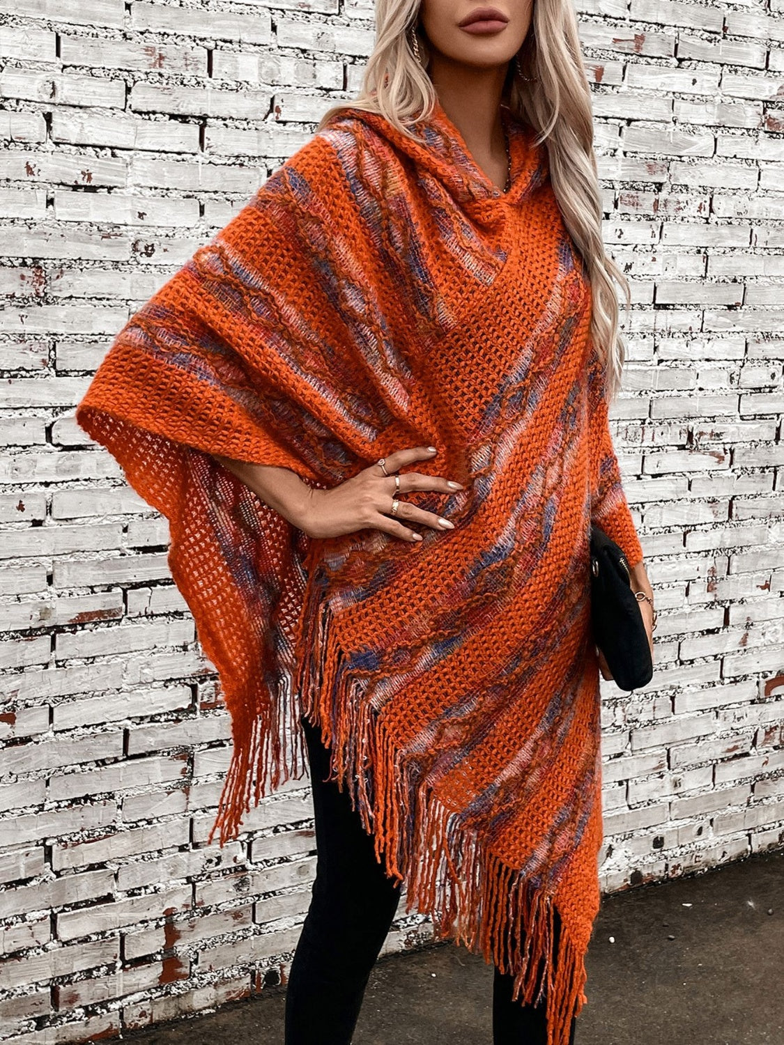 Terracotta knit hooded fringed cape with colorful threads and open weave.