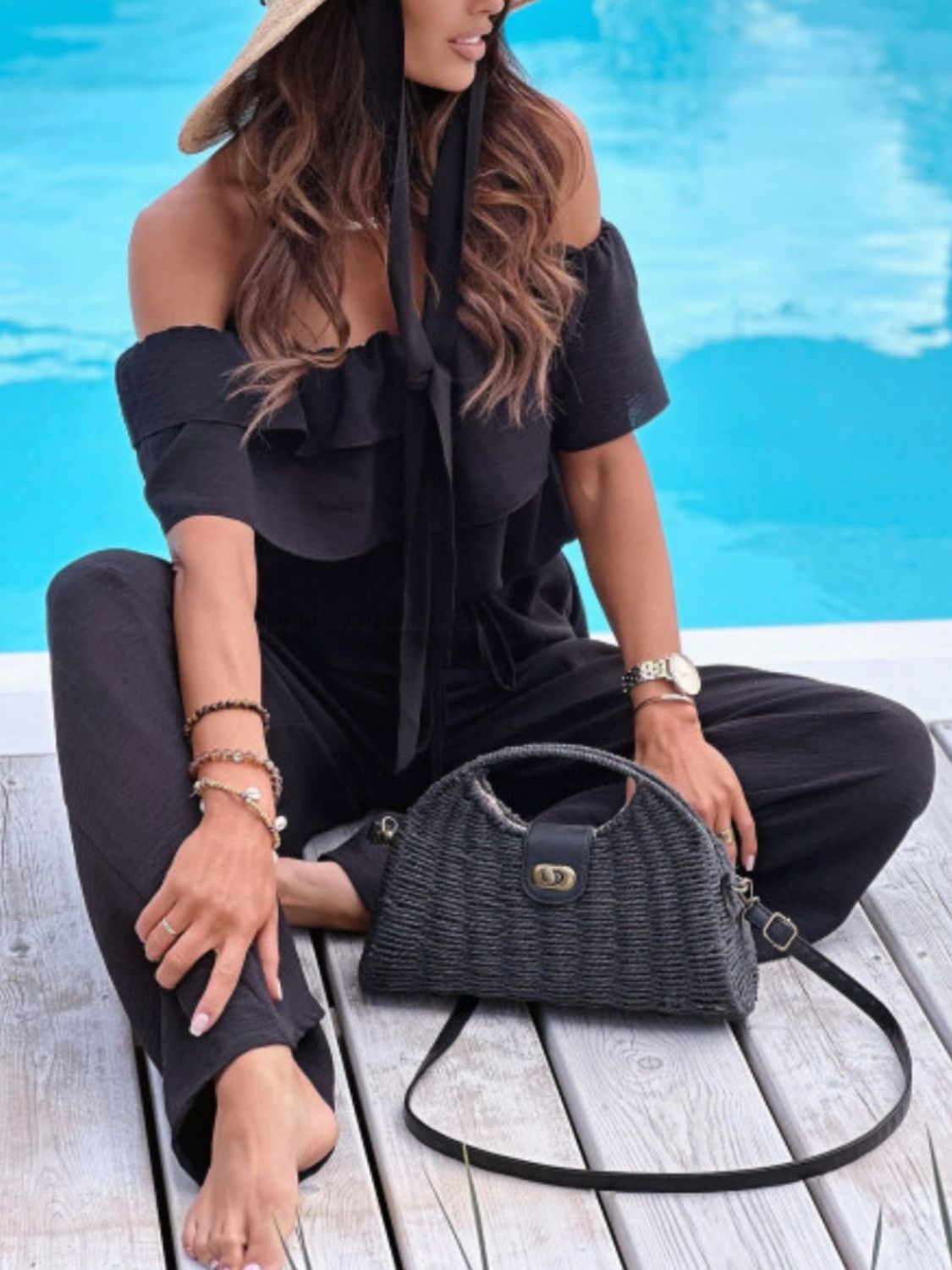 Black off-shoulder ruffle palazzo jumpsuit with tie detail and wide legs.