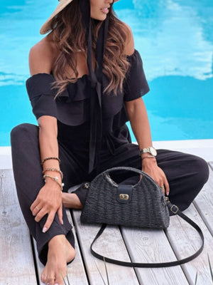 Black off-shoulder ruffle palazzo jumpsuit with tie detail and wide legs.